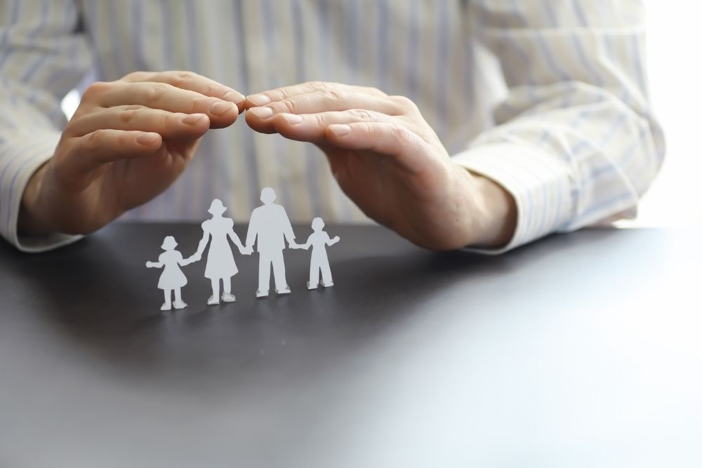 man-in-white-shirt-hand-protect-paper-family-of-four-term-life-insurance