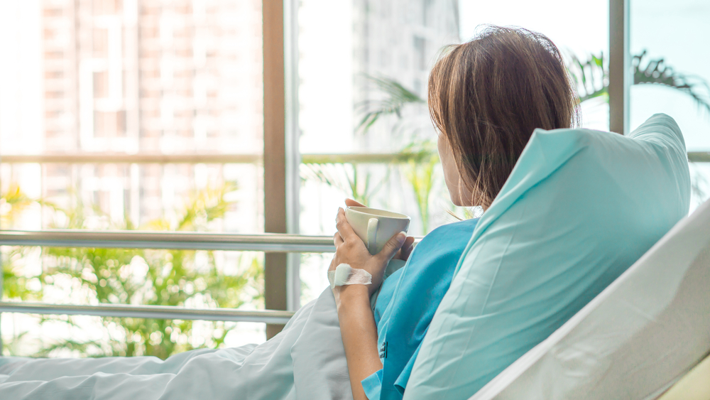 recovering young woman in hospital bed looking out window